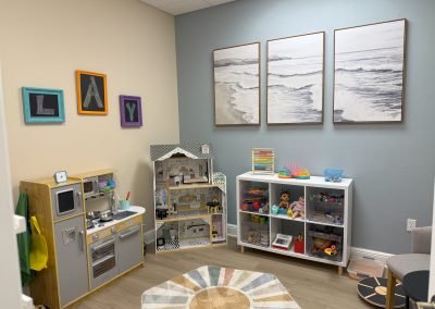 IMG_8338 Fort Myers Florida Play Therapy Room at the Fort Myers location, a play kitchen, doll house and shelf with toys.
